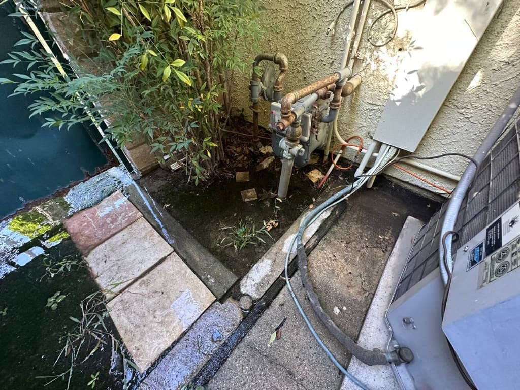 Severe water ponding and poor drainage near gas meter and HVAC equipment along foundation wall