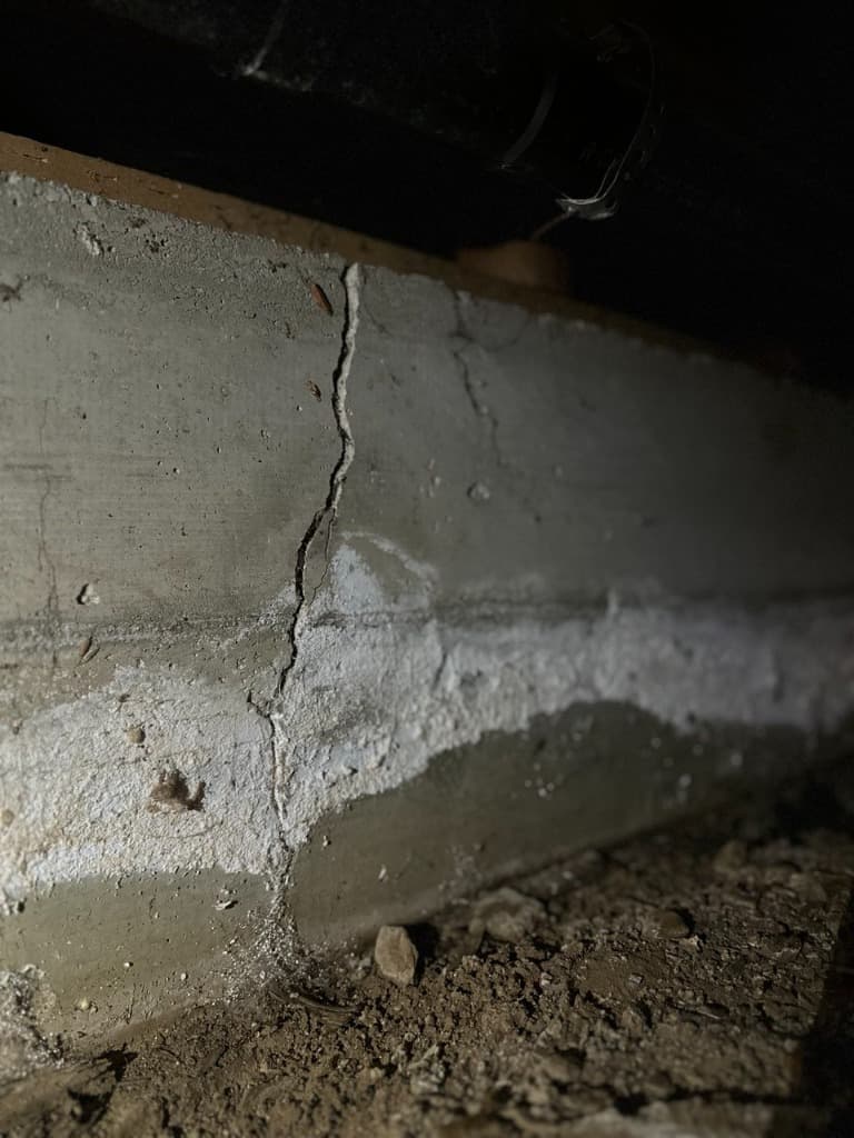 Severe efflorescence and salt deposits along crawl space foundation wall indicating chronic groundwater passage