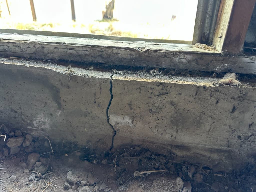 Open vertical fracture beneath sill framing where concrete has separated into independent segments